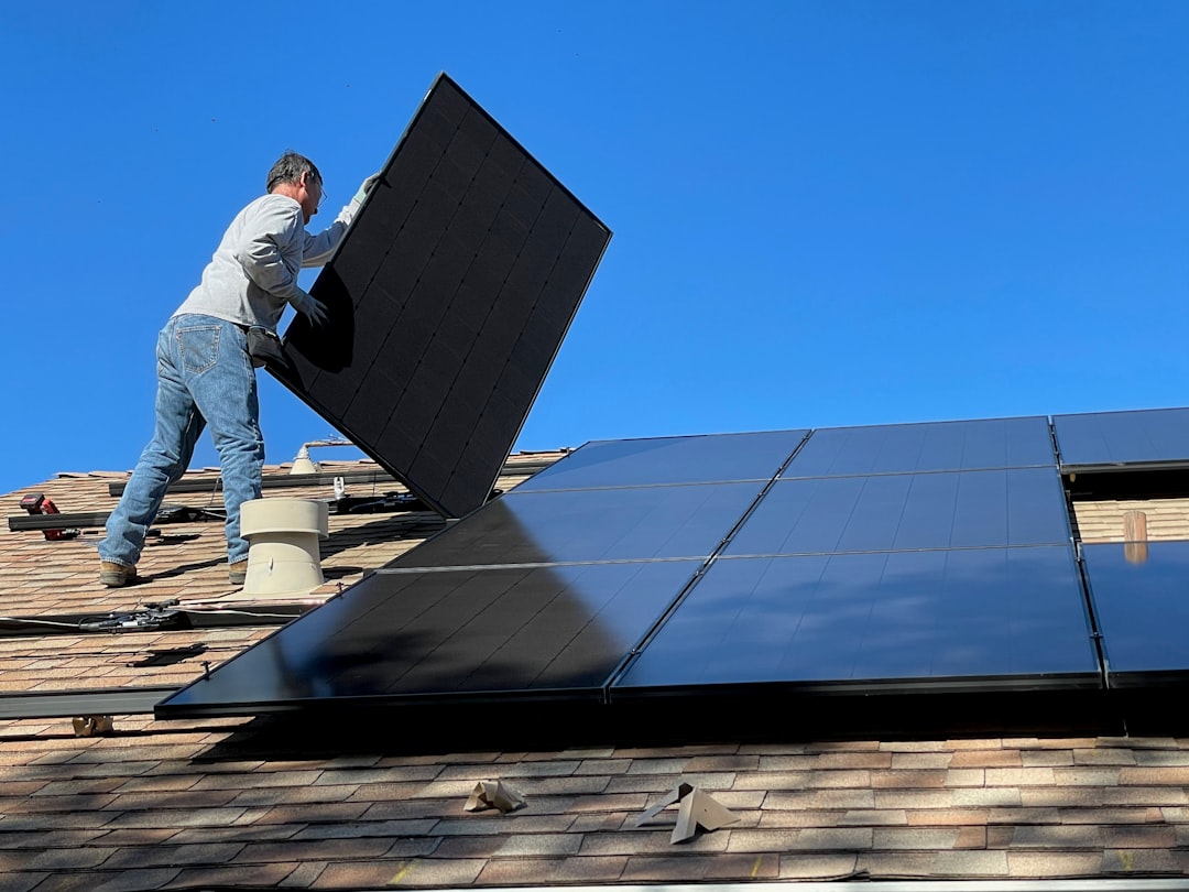 about-us-01 Worker installing solar panels on a roof